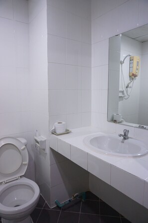 A bathroom with a toilet, sink, and mirror. - A.P. Court Hotel (Mueang Loei)