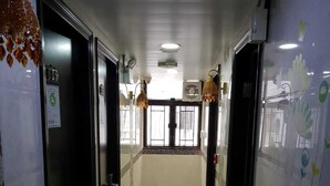 A corridor with doors, a tiled floor, and a window with a view. - Tom's Guest House (Kowloon)