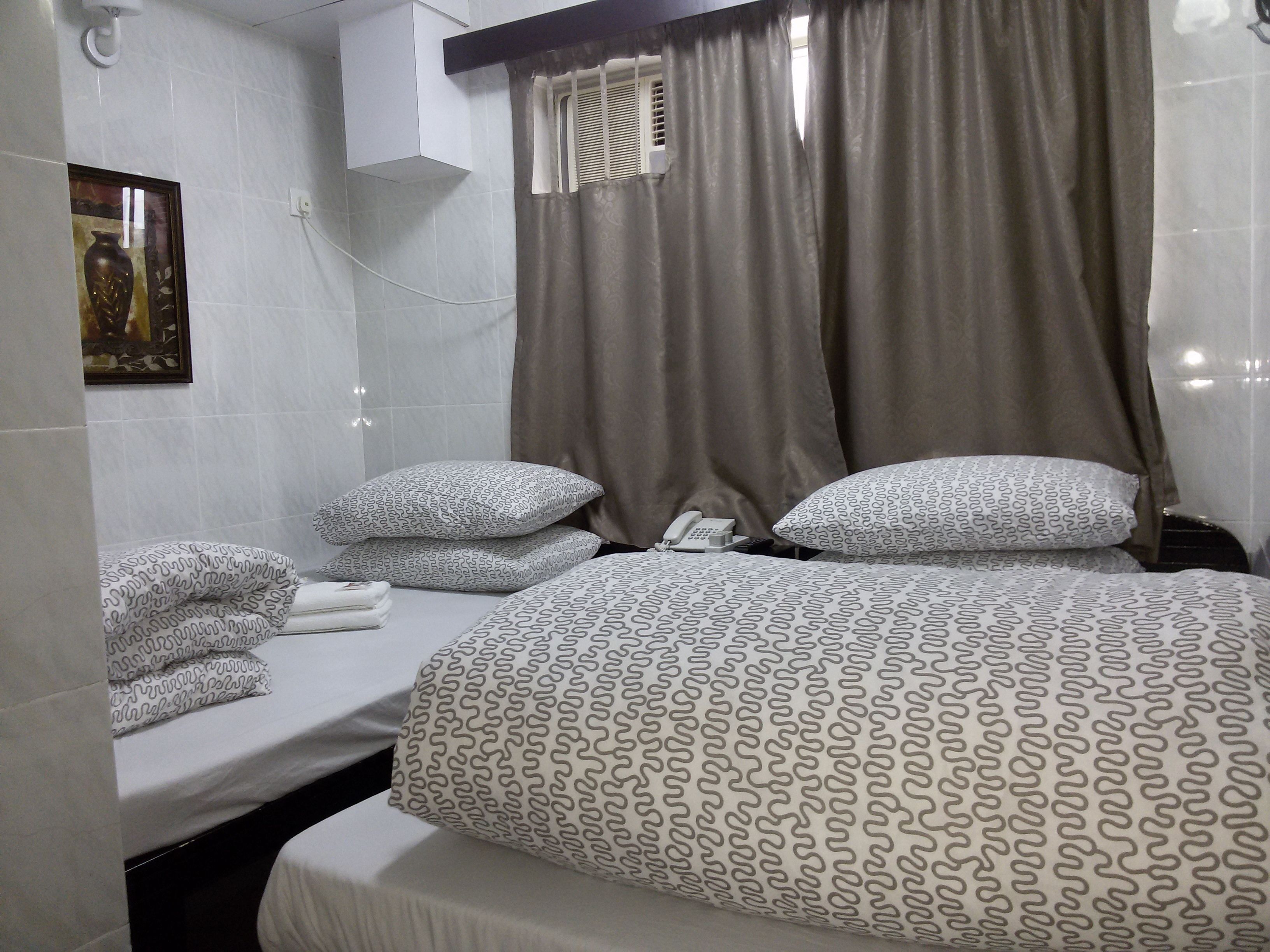 Une chambre d’hôtel avec un lit, deux oreillers, une table de chevet avec un téléphone et un porte-serviettes.