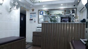 A reception area with a wooden counter, a fan, a printer, and a bench. - Tom's Guest House (Kowloon)
