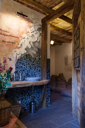 A rustic interior with a stone mosaic sink, wooden beams, and a wicker basket. - Resort Alt-Ötztal (Sautens)
