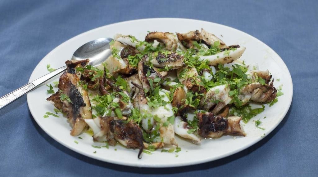 Un plato de pulpo a la parrilla, adornado con hierbas.