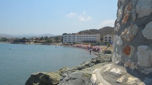 Hotel à beira-mar com área de piscina, guarda-sóis e vista para o mar.