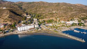 Uma cidade costeira com um porto de recreio, edifícios e colinas ao fundo.