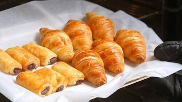 A tray of pastries, including croissants and chocolate-filled pastries, on a white paper.