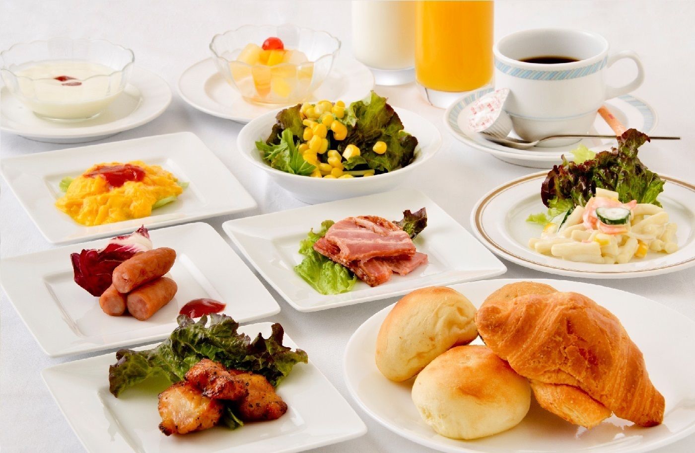 Un desayuno con diversos platos, incluyendo huevos, tocino, salchichas y bollería.