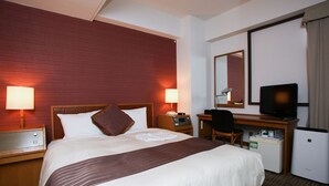 Hotelkamer met een groot bed, twee bedlampen, een bureau met stoel, een televisie en een minibar.