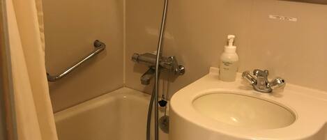Un baño con bañera, lavamanos, ducha y una toalla con la inscripción "WHG".