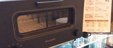 Un horno microondas negro con ventana de vidrio y panel de control, con el texto 'Balmuda'.
