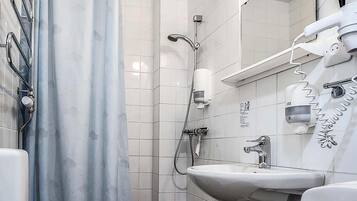 Un baño con ducha, lavabo y espejo.