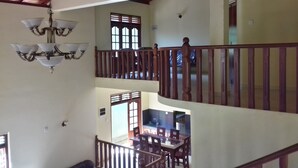Un intérieur à plusieurs niveaux comprenant un coin repas, des rampes en bois et un lustre.