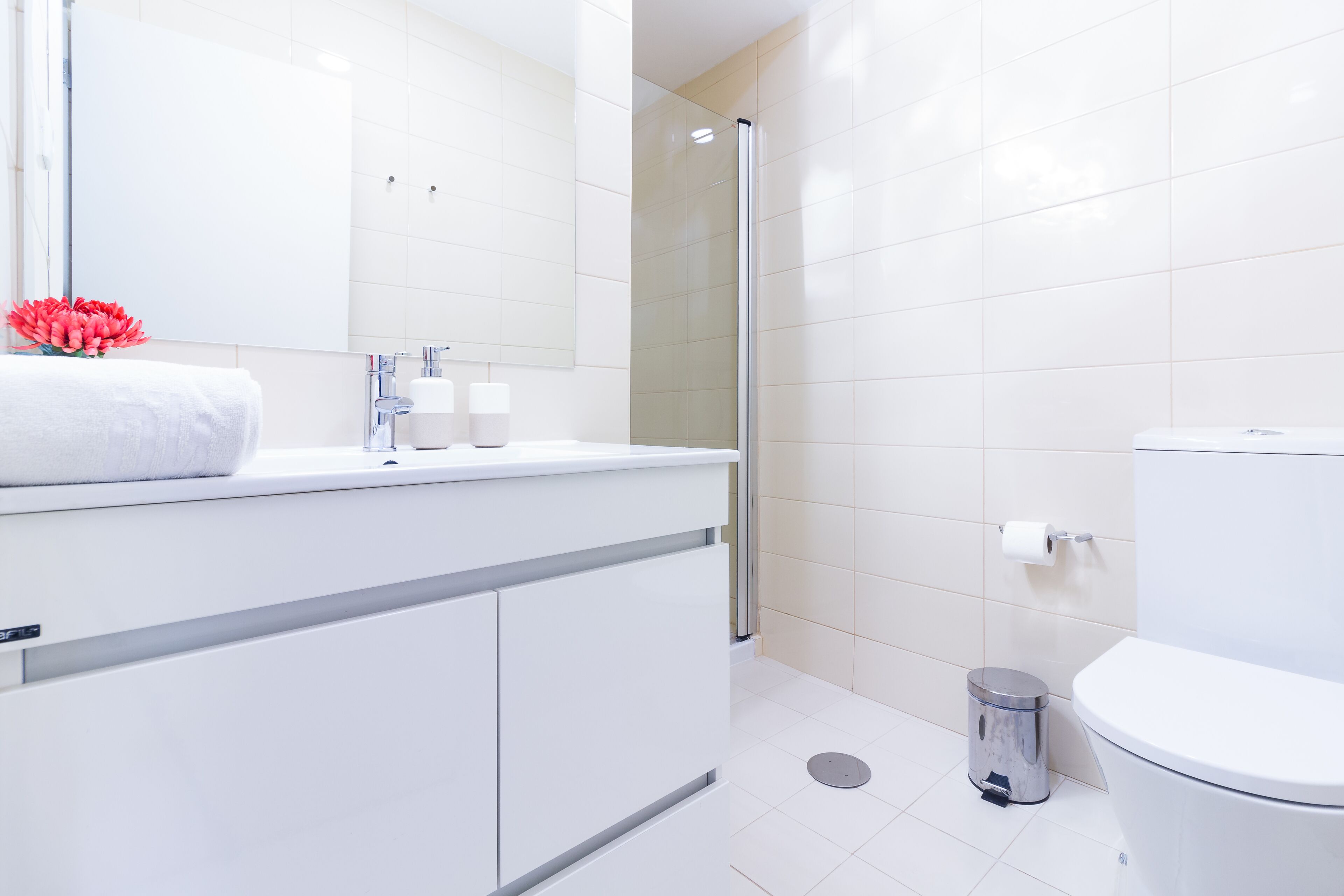 A modern bathroom with a white vanity, a glass shower enclosure, and a toilet.