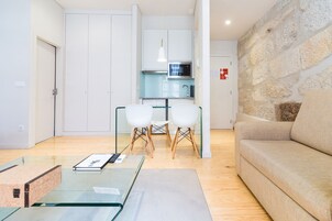 Un salon moderne avec une table basse en verre, un canapé beige et un mur décoratif en pierre.