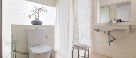 A modern bathroom with a toilet, shower, and sink.