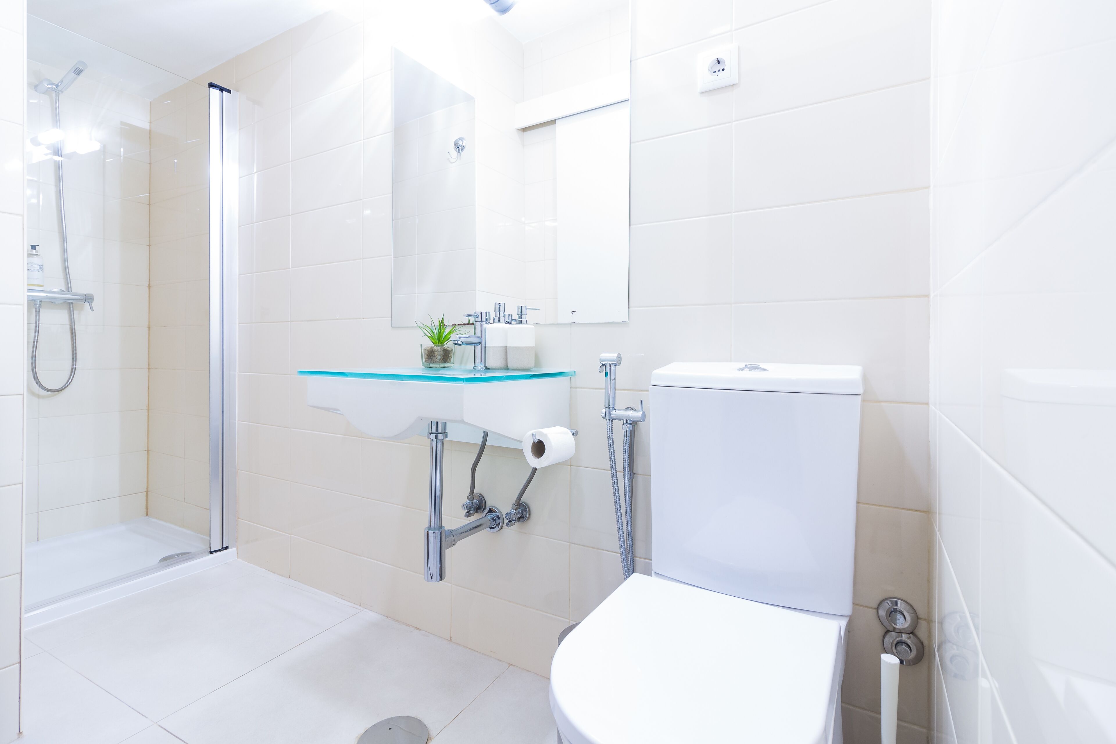 Un baño moderno con lavamanos de vidrio, inodoro y ducha.