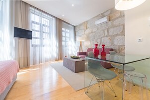 Un salon moderne avec un téléviseur à écran plat, une table à manger en verre et un mur en pierre.
