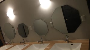Ein Badezimmer mit drei Waschbecken und mehreren Spiegeln an der Wand.