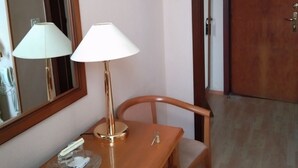 A hotel room with a wooden desk, two lamps, a chair, a mirror, and a door. - Domus Hotel -1 (Kyiv)