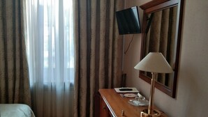 A hotel room with a bed, a desk with a lamp, a TV, and a chair. - Domus Hotel -1 (Kyiv)