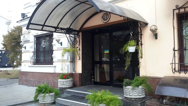 A hotel entrance with a covered awning, a black door, and potted plants at the steps. - Domus Hotel -1 (Kyiv)