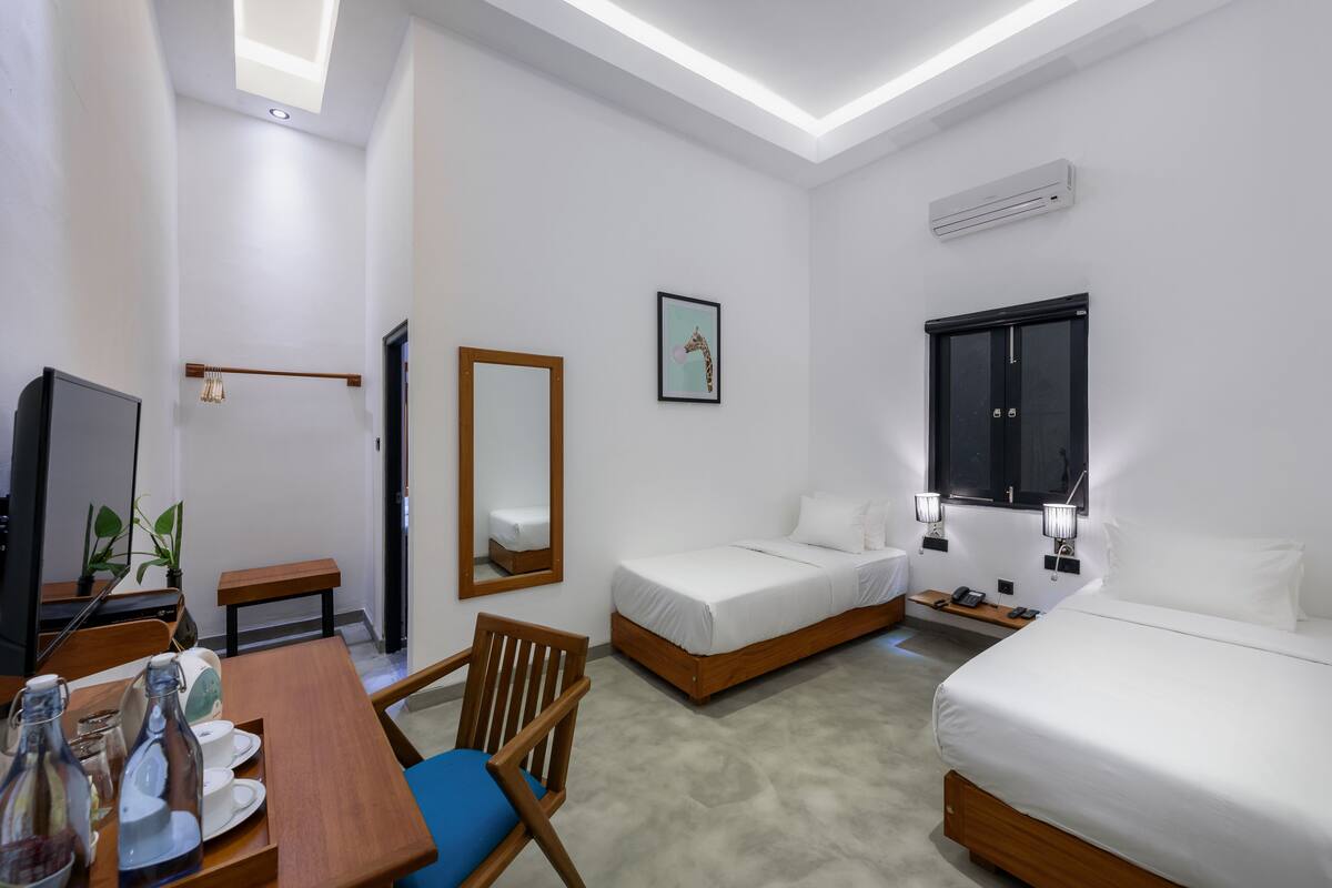 A hotel room with a bed, a desk with a chair, a TV, and a mirror.