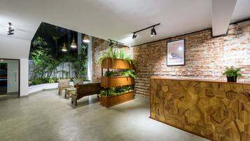 Un interior moderno con pared de ladrillo, mostrador de recepción de madera y plantas en macetas.