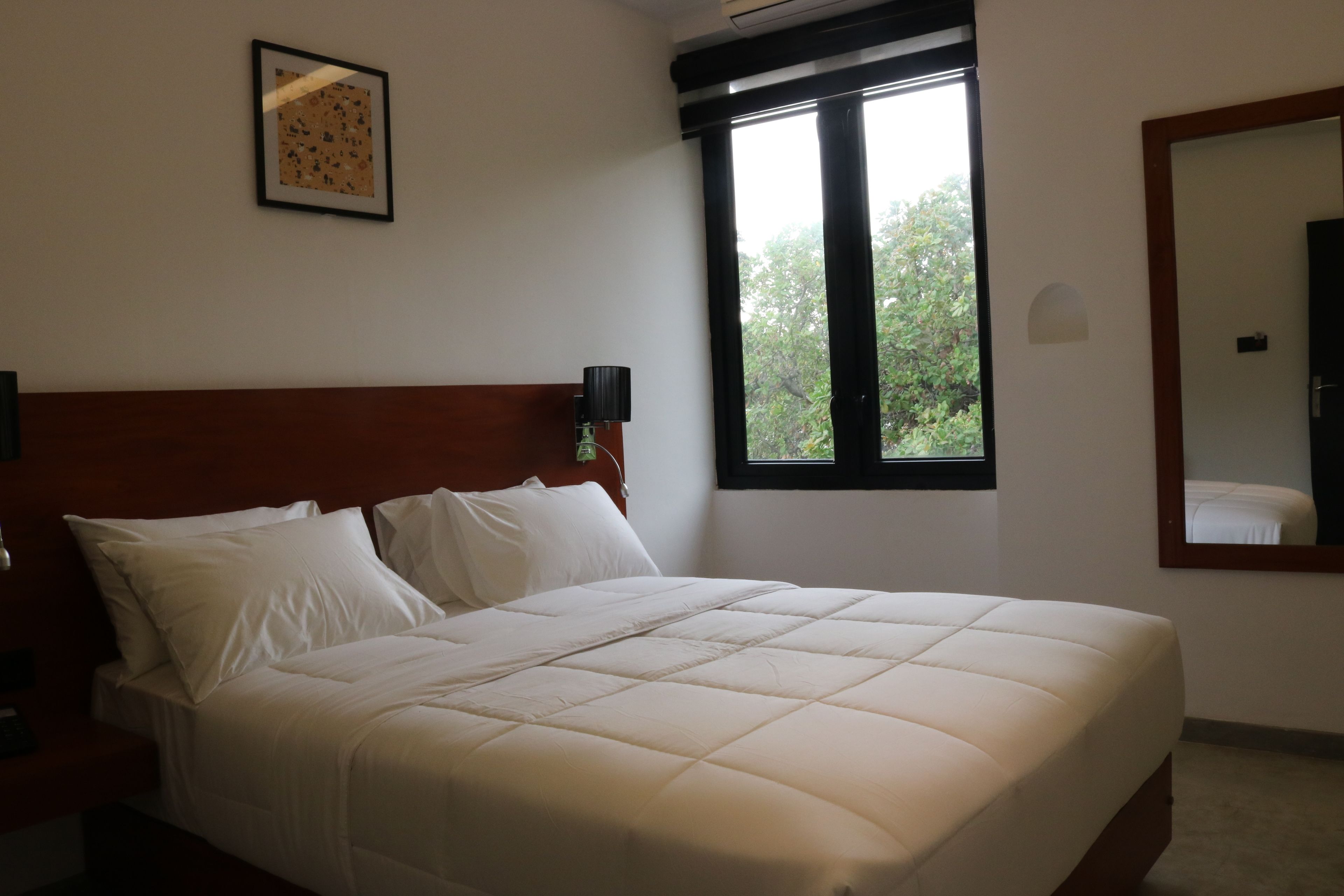 A neatly made bed with white linens in a hotel room.
