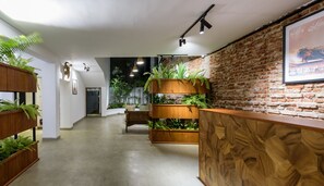 A modern interior with a brick wall, wooden shelving with plants, and a wooden reception desk. - Fern Colombo (Colombo)
