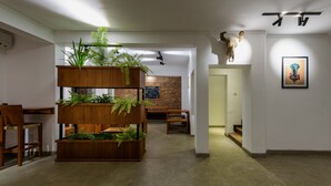 A modern interior with a wooden planter with plants, a brick wall, and a ceiling-mounted light fixture. - Fern Colombo (Colombo)