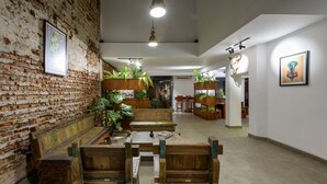A spacious interior with a brick wall, wooden furniture, and hanging plants. - Fern Colombo (Colombo)