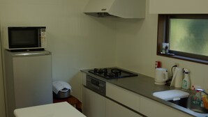 Cocina compacta con microondas, estufa, pileta y una ventana sobre la encimera.