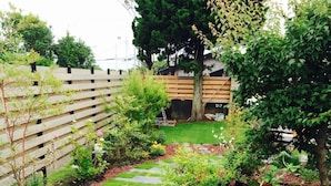 Un sendero en un jardín con escalones de piedra y césped verde.