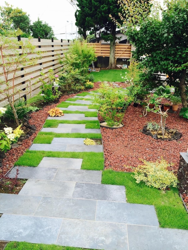 A garden pathway with stone steps and green grass.