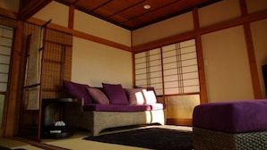 Una habitación japonesa tradicional con suelo de tatami, techo de madera bajo y puertas correderas shoji.