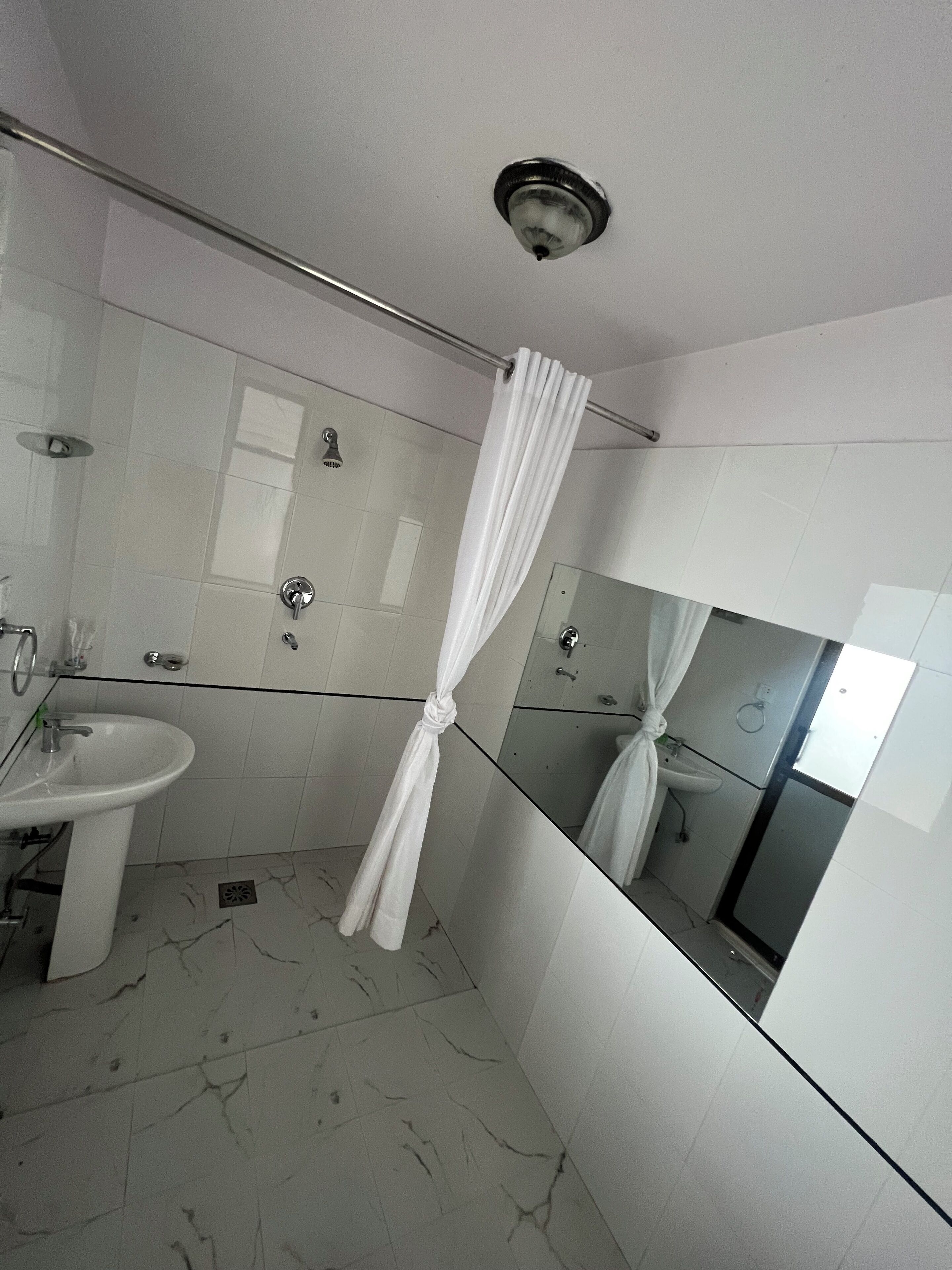 A bathroom with a shower, a sink, and a mirror.