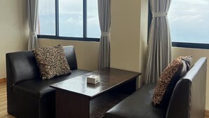 Una habitación moderna con dos sofás de cuero, una mesa de centro de madera y ventanas grandes con cortinas.