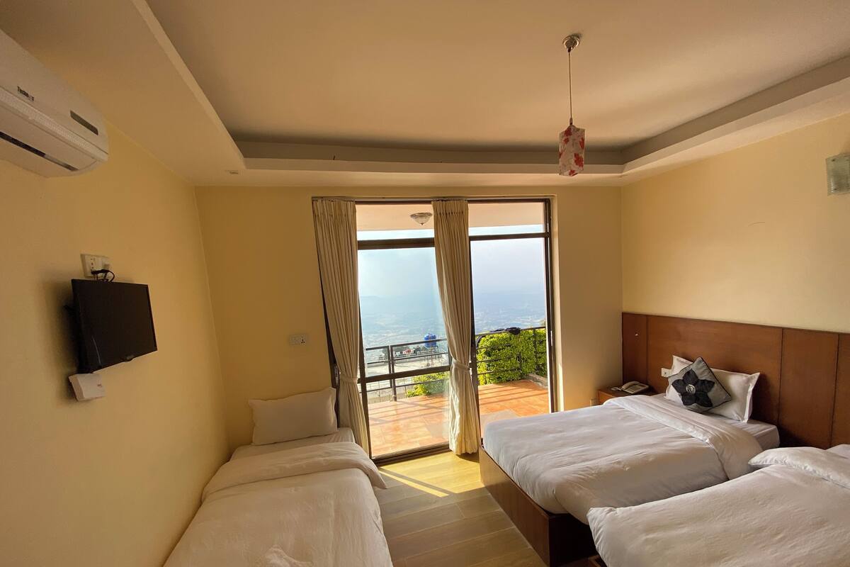 A hotel room with two beds, a TV, and a balcony with a view.