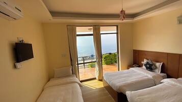 A hotel room with two beds, a TV, and a balcony with a view.