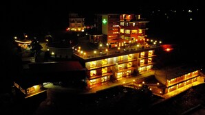 Un hotel de varios pisos con balcones iluminados y un letrero verde que indica un restaurante.