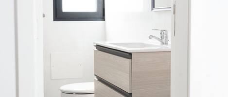 Un baño moderno con inodoro, lavabo y espejo.