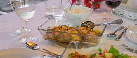 A dining table set with plates, glasses, cutlery, and a variety of dishes including a salad and roasted chicken.