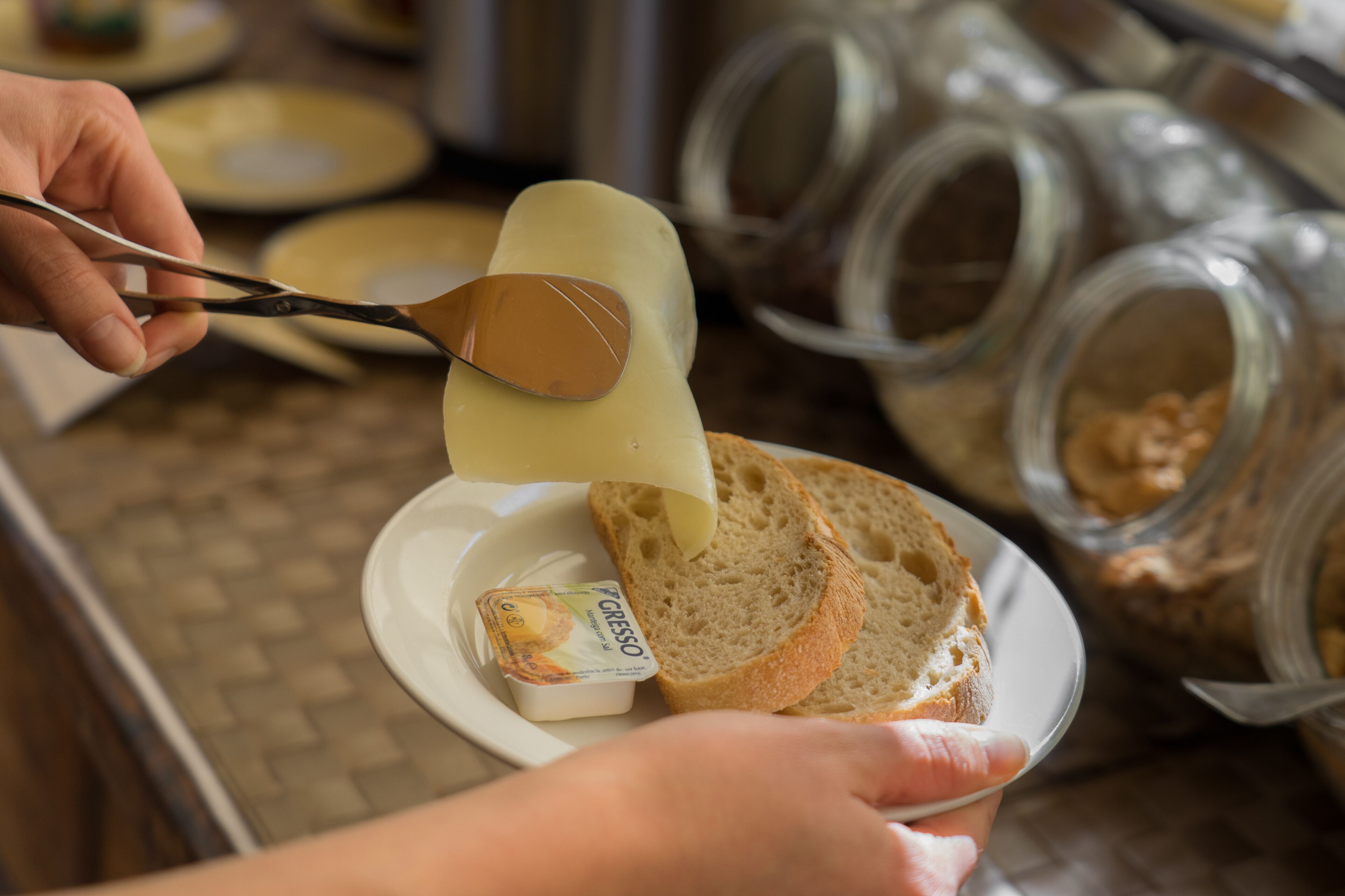 Una persona extendiendo una crema sobre una rebanada de pan en un plato.