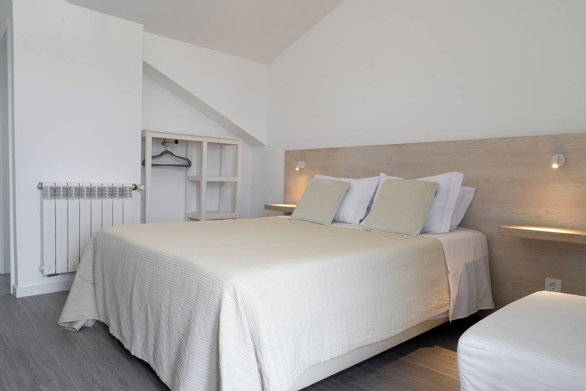 A bedroom with a large bed, a wooden headboard, a bedside table with a lamp, and a built-in wardrobe.