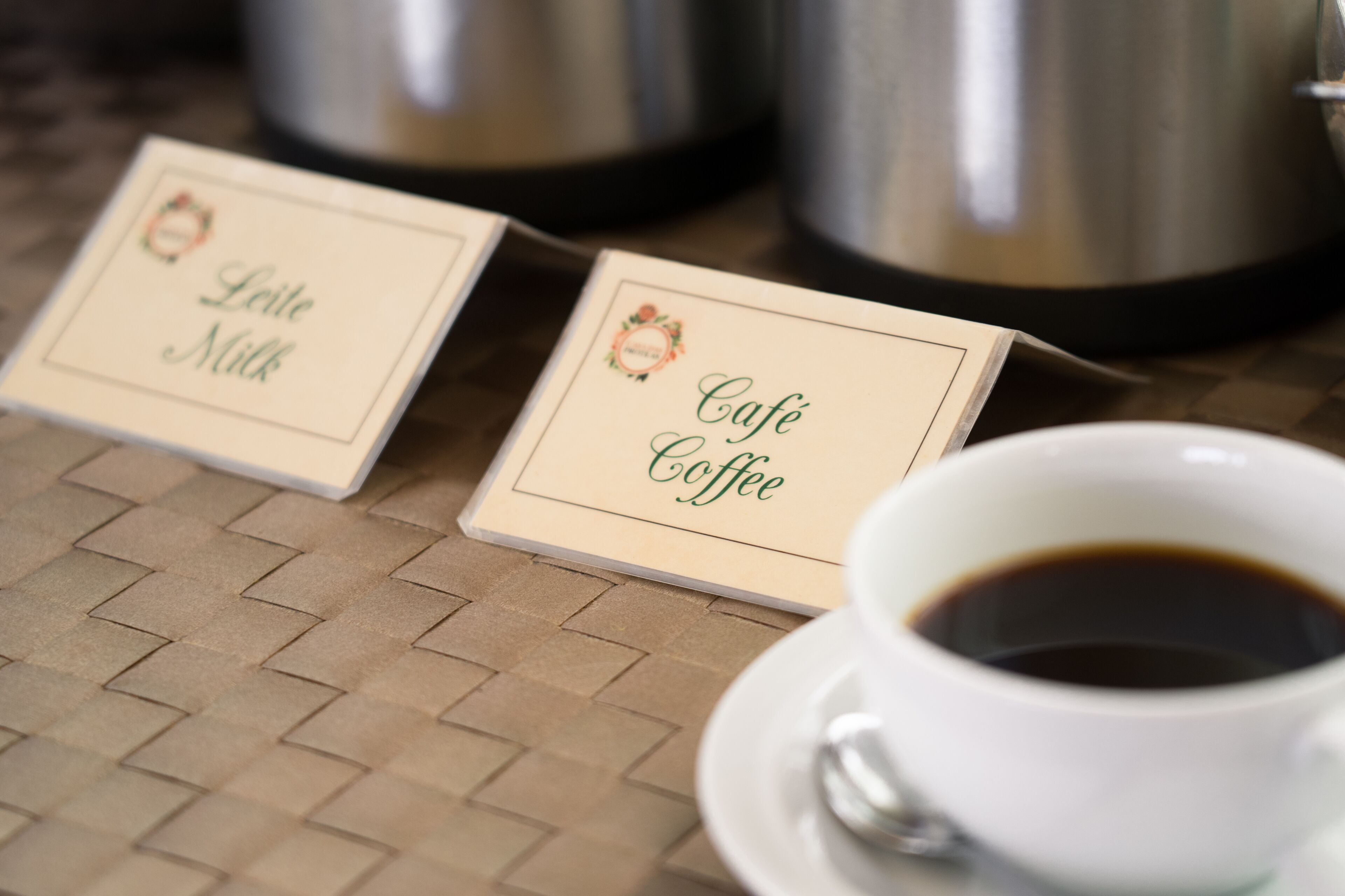Deux tasses à café sont posées sur une table, accompagnées de deux sets de table étiquetés « Café » et « Lait ».