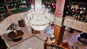 A grand lobby with a marble staircase, a large chandelier, and festive decorations. - Hotel Pamporovo (Chepelare)