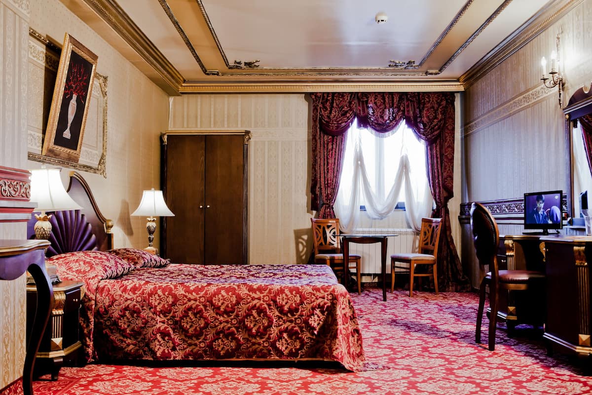 A hotel room with a large bed, a desk with a computer, a chair, and a television.