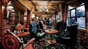 A room with vintage furniture, a chandelier, and a large window with a view. - Hotel Pamporovo (Chepelare)
