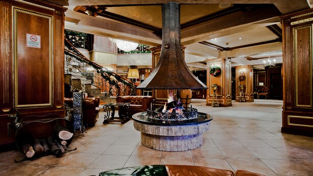 A grand lobby with a large, ornate fireplace, a staircase, and leather seating areas. - Hotel Pamporovo (Chepelare)