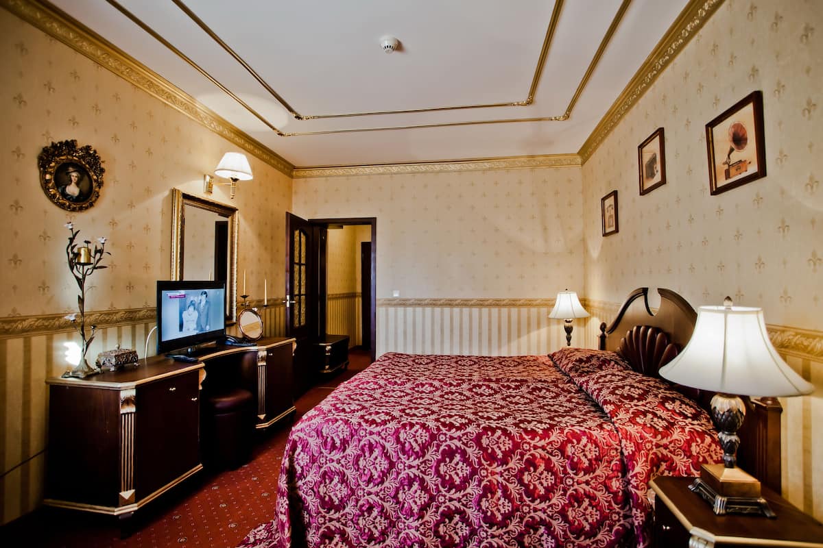A hotel room with a large bed, a television, a dresser, and a mirror.