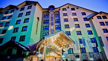 A hotel with a central tower, multiple windows, and a well-lit entrance.